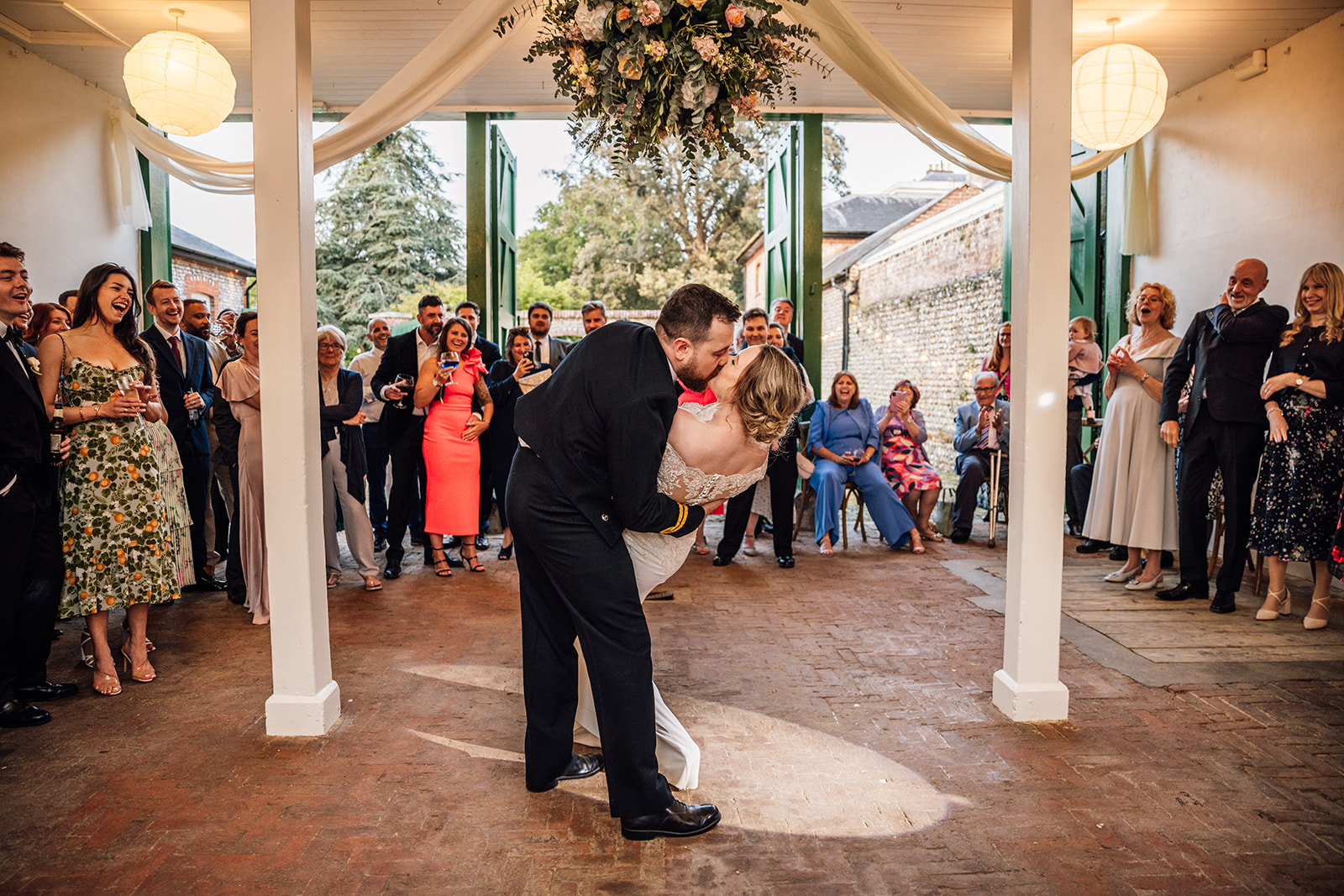 couple-dancing-in-bignor-park-barn-with-flowers-hanging-from-the-ceiling